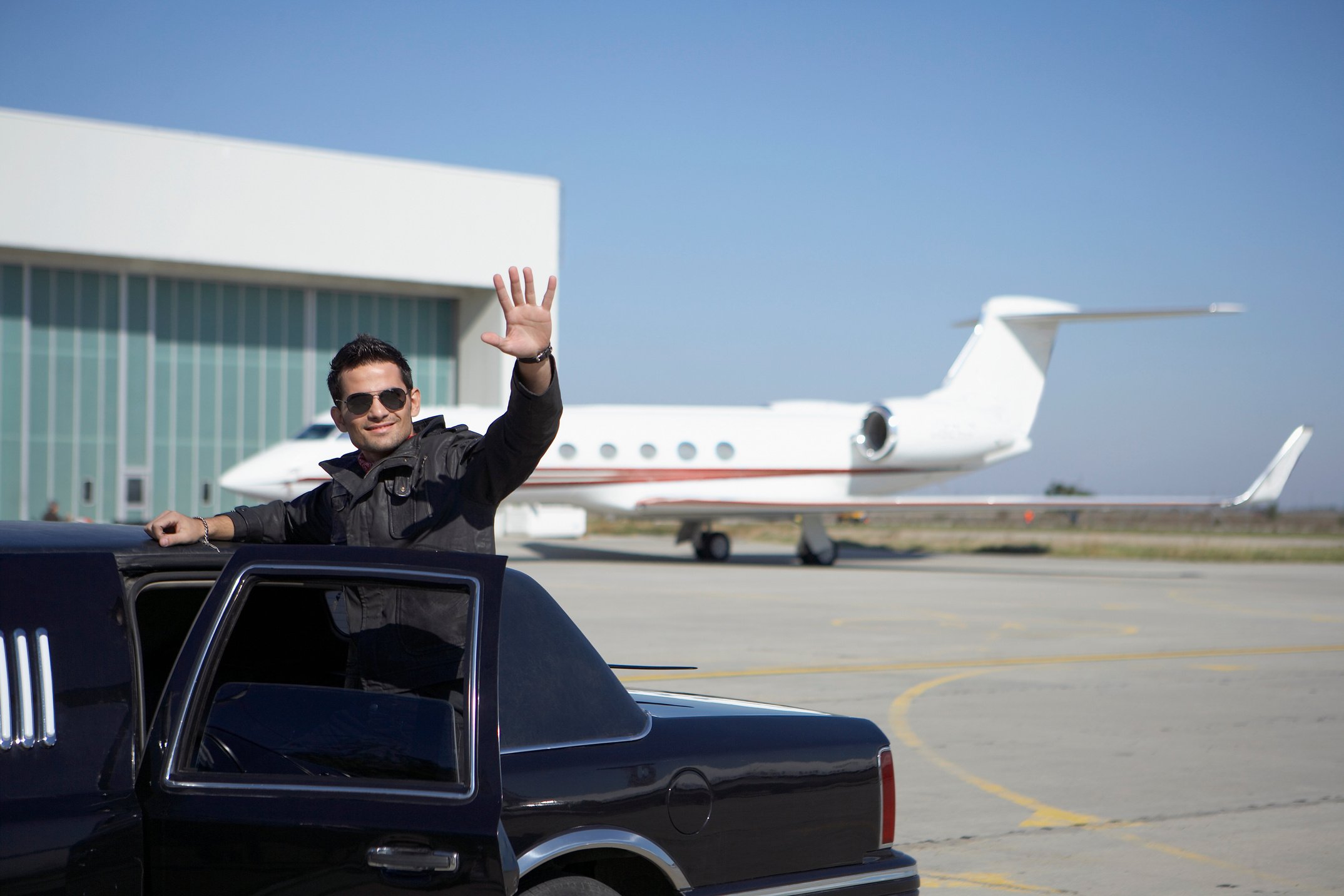 Man waving from limo at airport